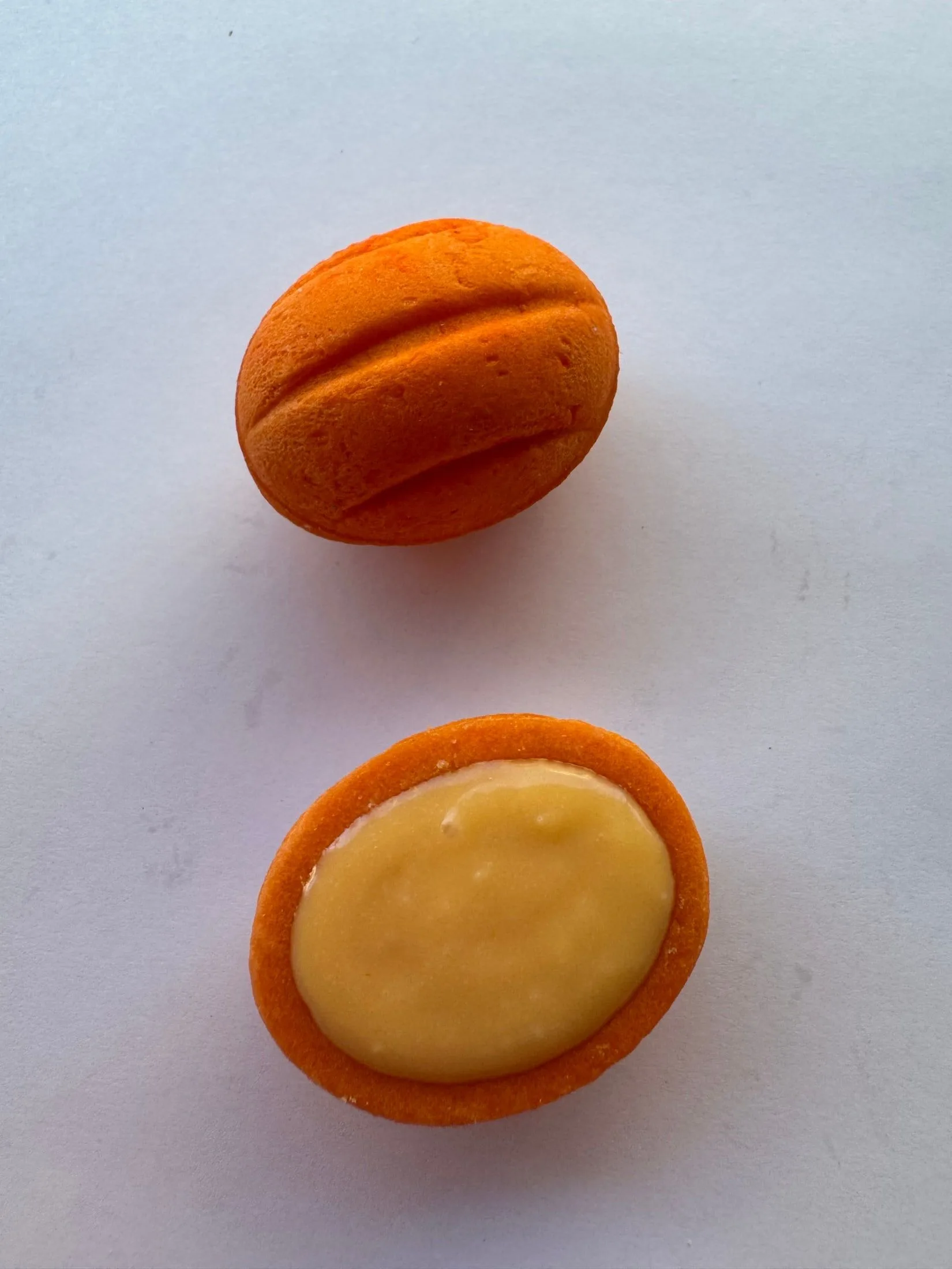 Un oreshki naranja entero y otro abierto, mostrando la crema de maracuyá